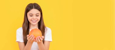 Greyfurtlu mutlu genç kız. Vitamin ve diyet. Çocuk sağlıklı yiyecekler yiyor. Greyfurt portakallı çocuk portresi, yatay poster. Kopyalama alanı olan başlık