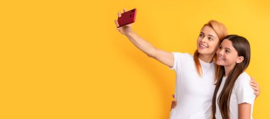 Anne ve kız çocuk afişi, kopyalama alanı, izole bir arka plan. Akıllı telefondan selfie çeken anne, kadın ve kız çocuklarının neşeli aileleri.