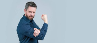 Olgun bir adam L şeklinde kollarını büker, yumruğunu yukarı kaldırır ve müstehcen hareketler yapar. İnsan yüzü portresi, kopyalama alanı olan pankart