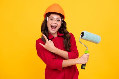 Kasklı, fırçalı çocuk ressamı. Kasklı çocuk. İnşaat alanında boyacı çocuk. Yenileme ve onarım. Heyecanlı genç kız