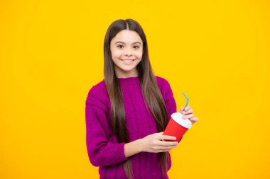 Sarı stüdyo arka planında kahve ya da çay fincanı olan çocuk. İçki ısmarlayan ergen kız.