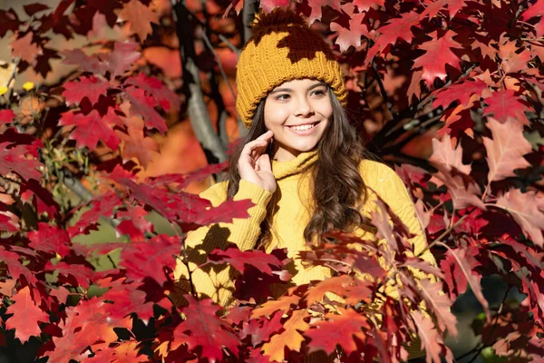 Teenager girl on autumn fall background. happy kid face in hat at autumn leaves on natural background.