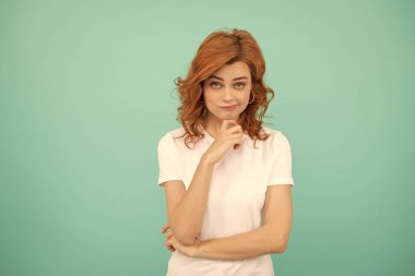 Mavi arka planda kıvırcık saçlı kızıl saçlı bir kadın..