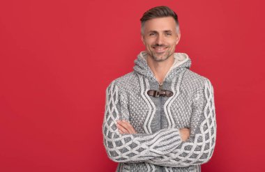Kırmızı arka planda süveter giyen gülümseyen adam fotokopi alanı, moda.