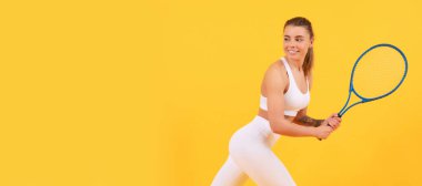 Sırıtkan tenisçi sarı arka planda raketle koşuyor. İzole edilmiş yüz portresi, kopyalama alanı oluşturulmuş pankart