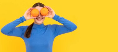 İzole edilmiş yüz portresi, fotokopi alanı olan pankart. Sarı arka planda turuncu turunçgil meyvesi tutan komik genç kadın, vitamin