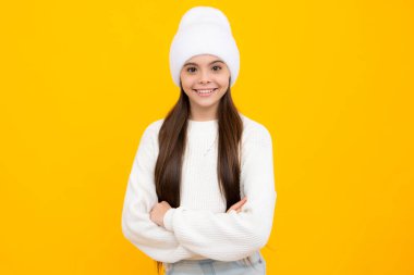 Confident child keep arms crossed, isolated on yellow background, empty space. Little caucasian teenage girl 12, 13, 14 years old hold hands crossed. Children studio portrait. Childhood lifestyle