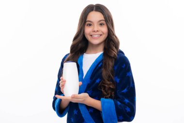 Teen child girl with shampoo bottle or shower gel isolated on yellow background. Kids hair cosmetic product. Happy girl face, positive and smiling emotions