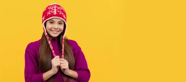 黄色い背景に冬の帽子をかぶった子供の笑顔ニットウェア クリスマスの子供の女の子のバナー スタジオの子供の冬の肖像画とともにコピースペース — ストック写真