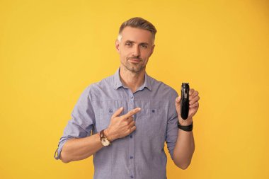 Gri saçlı adam elektrikli jilet sunuyor. Saç bakımı ve tıraş. Kişisel bakım ve cilt bakımı. Erkek güzelliği. Berber dükkanı. İşaret parmağı elektrikli tıraş makinesi..