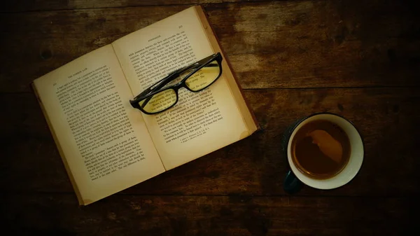 cup of coffee and books with book and other accessories on wood table.