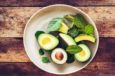 Kavanozda avokado ve taşrada yeşil yapraklı ahşap bir tabak..
