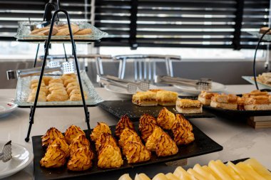 Her sabah kahvaltı servisi yapılan bir otelde bir masa. Tam bir kahvaltı, tepsiler dolusu tatlı kek ve hindistan cevizli kurabiye. Kahvaltı yapmak için bir sürü seçenek var..