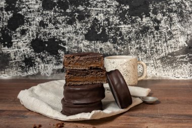 a stack of various chocolate cookies on wooden table, black and white textured background