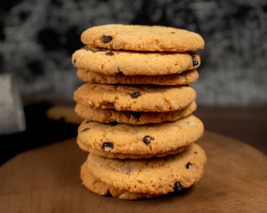 several homemade vanilla and chocolate cookies. on a wooden board. the background is textured and black and white