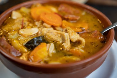 a very close up of a casserole with tripe. It is a food that is served hot to eat in winter. It also has some vegetables such as carrots and potatoes.