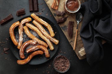 Churros - Kızarmış hamur tatlısı ve şeker tozu - sıvı çikolatalı koyu arkaplan