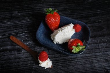 Kırsal bir zeminde taze çilekli krem şanti.