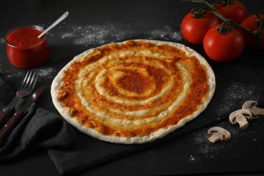 Siyah arka planda domates soslu pizza hamuru