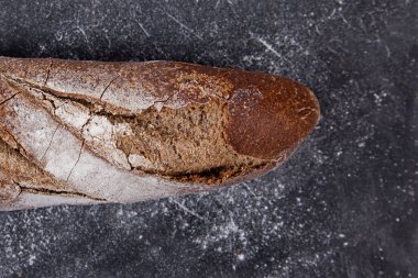 Bir somun ekmek yakın plan. Koyu arkaplanda taze pişmiş ekmek. Hamur işleri.