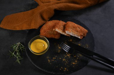 Kızarmış ekmek filetosu siyah bir tabakta servis edilir.