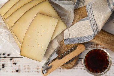 Beyaz ahşap arka planda tipik İspanyol Manchego peyniri ve şarabı dilimleri.