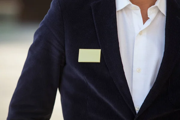 Blank identity tag hanging from a business man suit outdoors