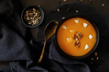 Koyu arkaplanda keçi peyniri ve tohumlu sıcak balkabağı kremi.