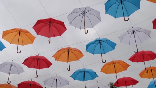 Colorful umbrellas hanging against overcast sky at outdoor festival: slow motion — Stock Video