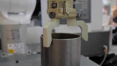 Endüstriyel robot kelepçe kol manipülatörü modern robot sergisinde silindirik metal iş parçalarını hareket ettiriyor ve yerleştiriyor. Üretim, mühendislik, ai, teknoloji kavramı