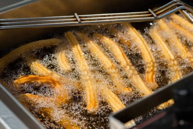 Sokak gıda pazarında kaynamış yağda churros pişirme işlemi: kapatın