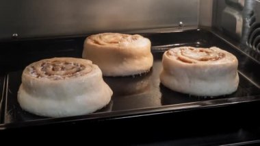 Zaman ayarlı - evdeki elektrikli fırında üç tarçınlı çörek pişiyor ve yükseliyor