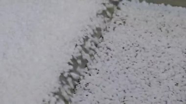 Yakın çekim: otomatik şist karıştırıcı üzerindeki geri dönüştürülmüş plastik granüller, taşıyıcı bant