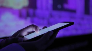 Sergide renkli ışıklandırmalı akıllı telefon kullanan kadın - yakın çekim
