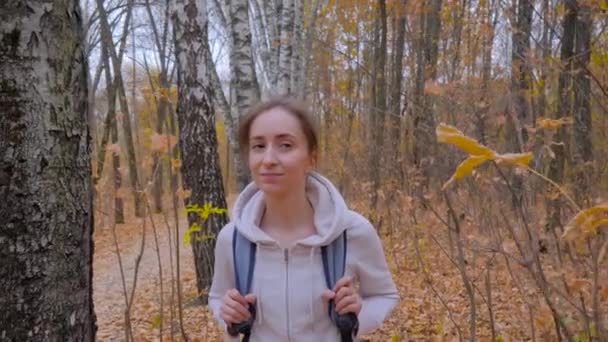 Junge Frau mit Rucksack spaziert im Herbstpark - Steadicam-Aufnahme — Stockvideo