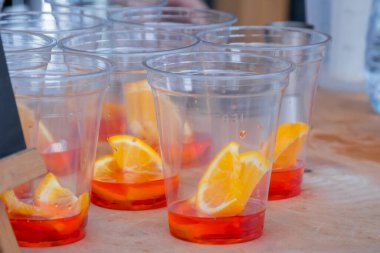Portakal dilimli plastik bardaklar ve tezgahta Spritz Aperol kokteyli. Yakın çekim.