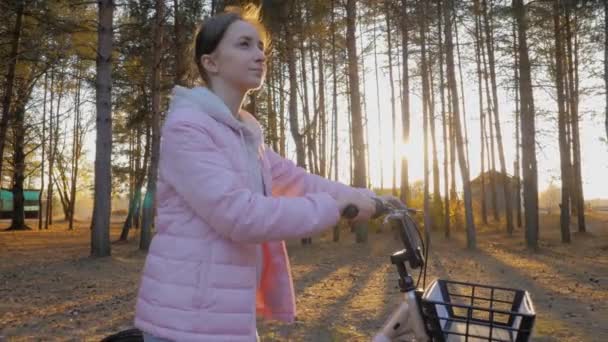 Повільний рух: молода жінка йде з велосипедом в осінньому міському парку — стокове відео