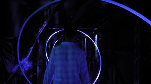青いイルミネーションの暗い廊下を歩く若い女性のバックビュー — ストック動画