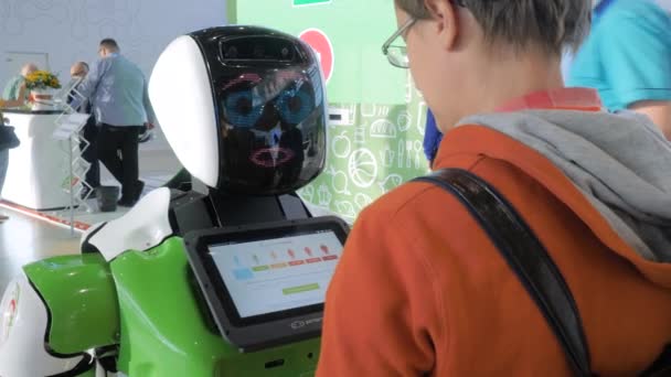 Λευκό χαριτωμένο ρομπότ με πρόσωπο οθόνη μιλώντας με τους ανθρώπους στο εμπόριο τεχνολογίας δείχνουν — Αρχείο Βίντεο