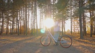 Sonbahar kozalaklı ormanlarında bisikletle yürüyen genç bir kadın - yavaş çekim