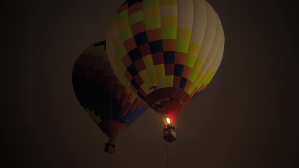 İki renkli sıcak hava balonu karanlık gökyüzüne karşı alevlerle uçuyor. — Stok video