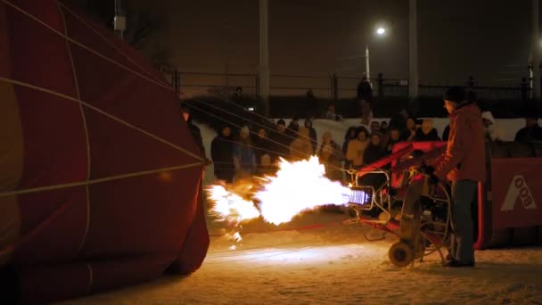 Люди, использующие газовую горелку и готовящие воздушный шар к запуску ночью — стоковое видео