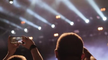 İnsanlar gece rock konserinde video kaydedip şeytan boynuzlarını gösteriyorlar.