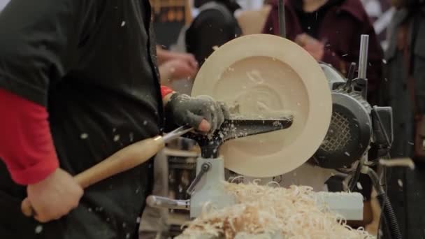Slow motion: man using chisel for shaping piece of wood on lathe with sawdust — Stock Video