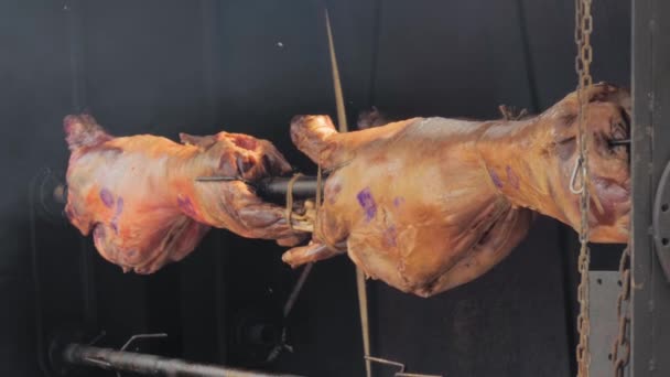 Process of cooking two ram carcasses on spit at street food market — Vídeo de Stock