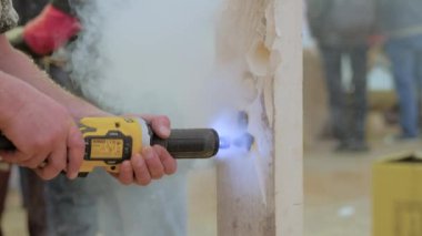 Man using grinder for carving wooden sculpture with smoke - close up