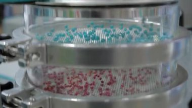 Many granules bouncing on platform of sieve shaker machine - close up