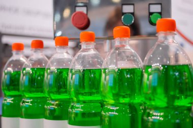 Row of pet bottles with green lemonade on conveyor belt - close up