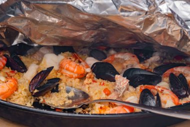 Close up: tablespoon and paella with shrimp, mussel - close up
