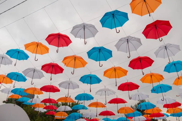 Colorful umbrellas hanging against overcast sky at outdoor festival